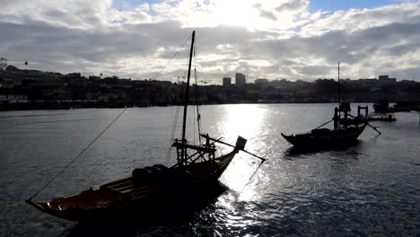 silhouette of rabelos boats moored on douro river at sunset, portugal