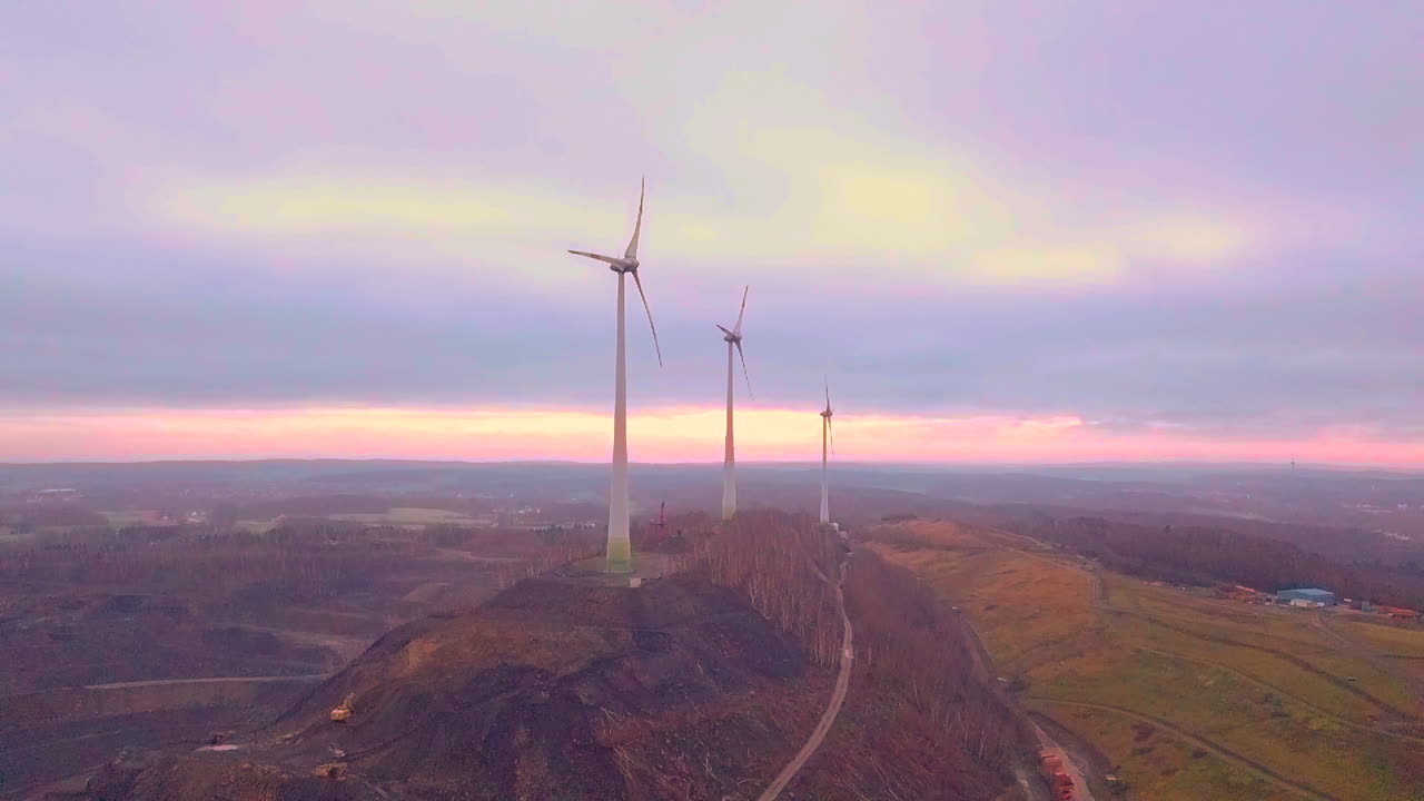 백그라운드에서 일몰 동안 언덕에 풍력 터빈 농장의 공중 샷