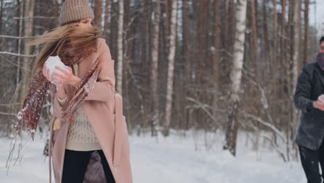 slow motion - couple snowball fighting in a field. they end their fight on a good terms with a high five.