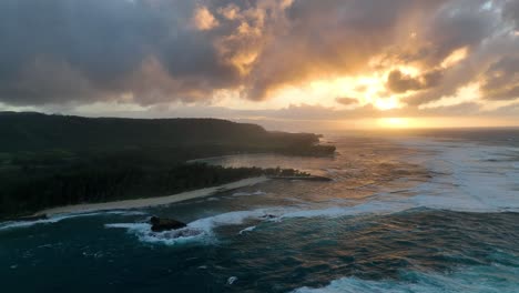 aerial drone shot of a large wave flowing across the ocean surface toward a rocky shore and beach around the sunset cliffs