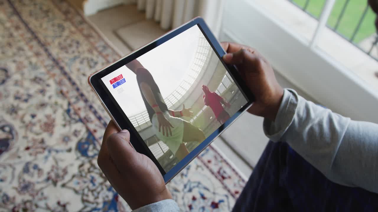compuesto de un hombre sentado en casa, viendo un partido de rugby en la tableta