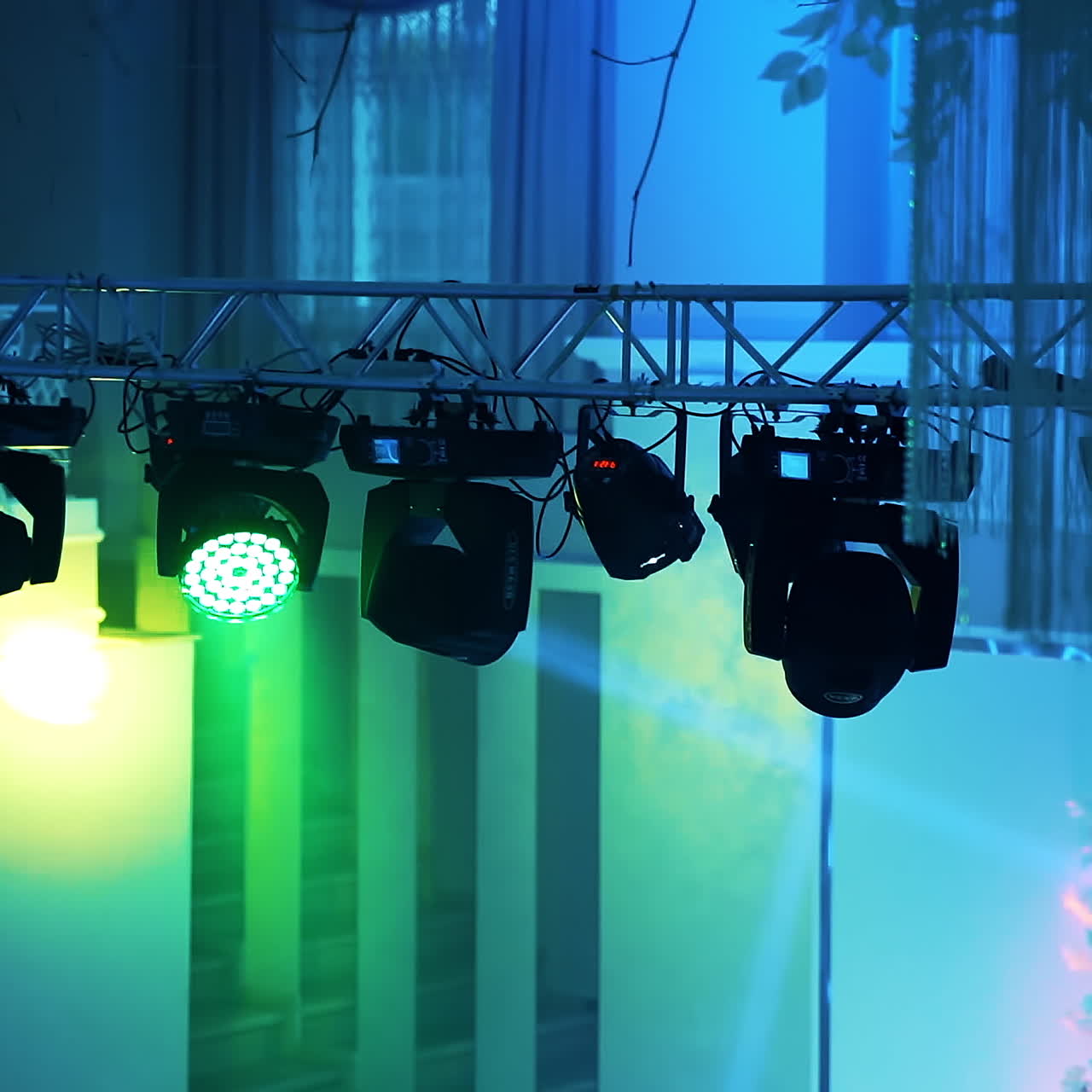 Blue background with colorful spotlights in the night club. Flashing rays with different colors glowing from projectors. Close-up.