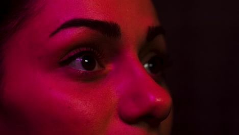 woman is amazed by what she sees on screen in the cinema lit with coloured lights