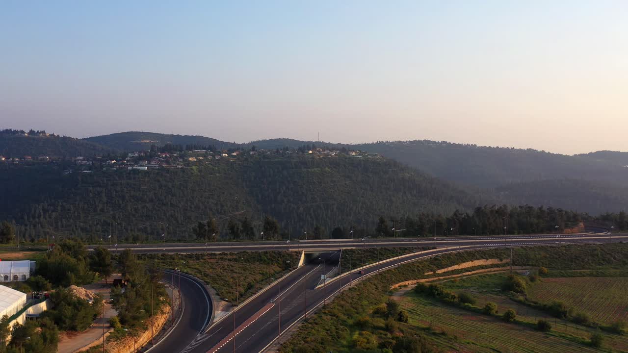 Aerial View of a Highway Interchange Winding Through a Green Hilly Landscape
