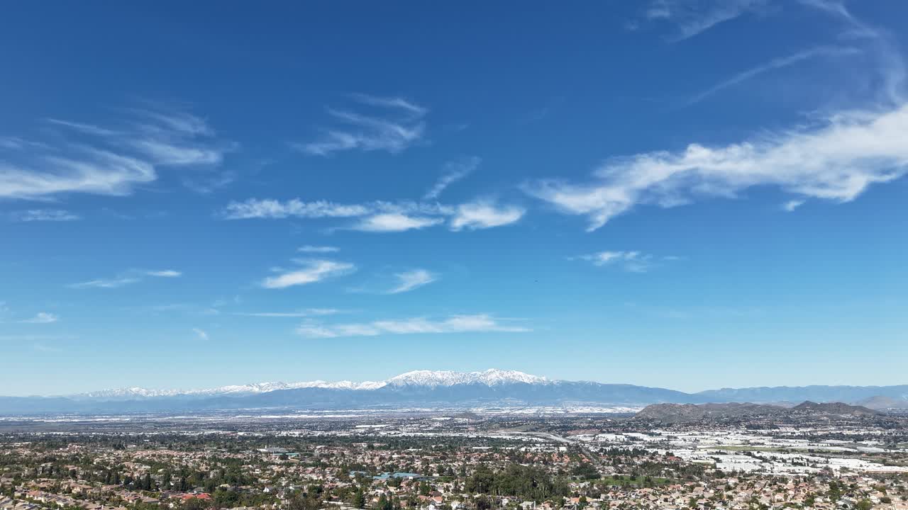 Nuvole bianche che scivolano dolcemente nel cielo con montagne innevate sullo sfondo in una giornata limpida e soleggiata