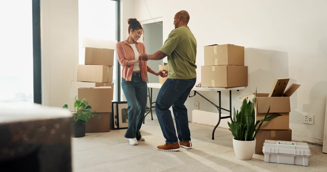 Happy Couple Dancing Together in Their New Home Surrounded by Moving Boxes