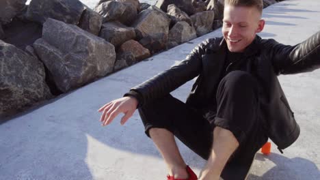 young man sits at his longboard and smiles