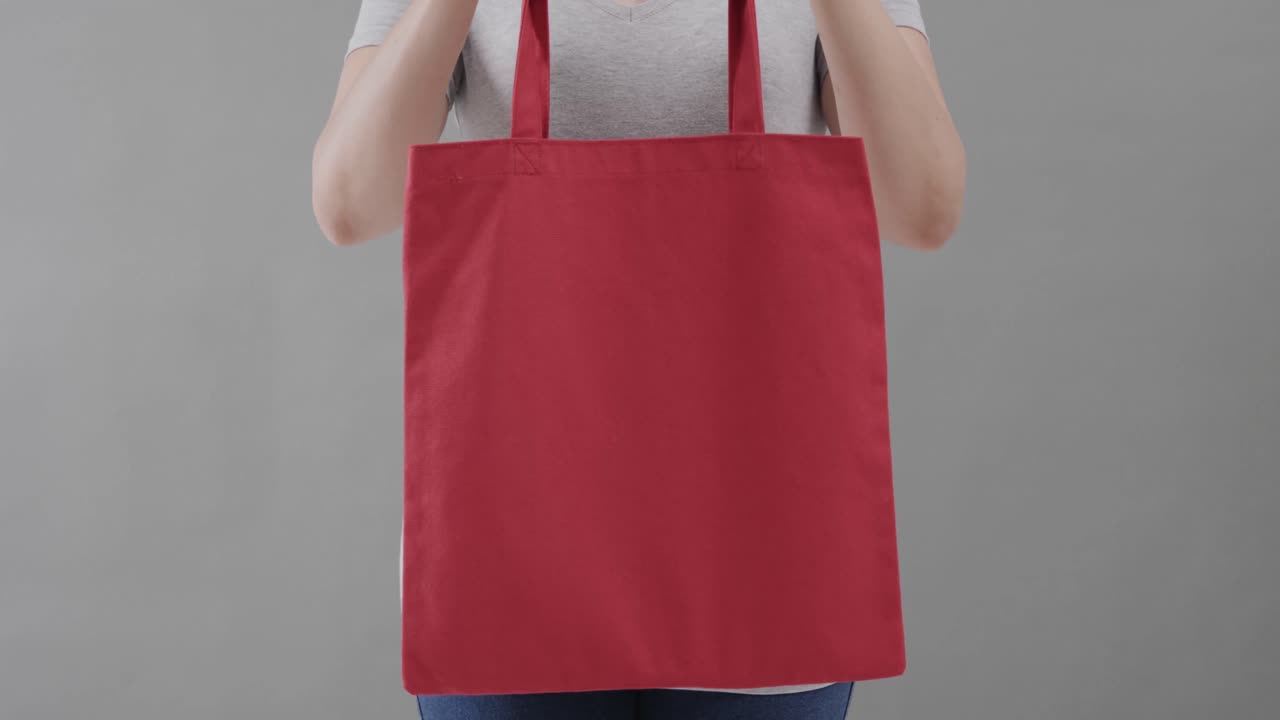 ⁇ 색 티셔츠를 입은 백인 여성이 회색 배경에 빨간 가방을 들고, 복사 공간, 슬로우 모션