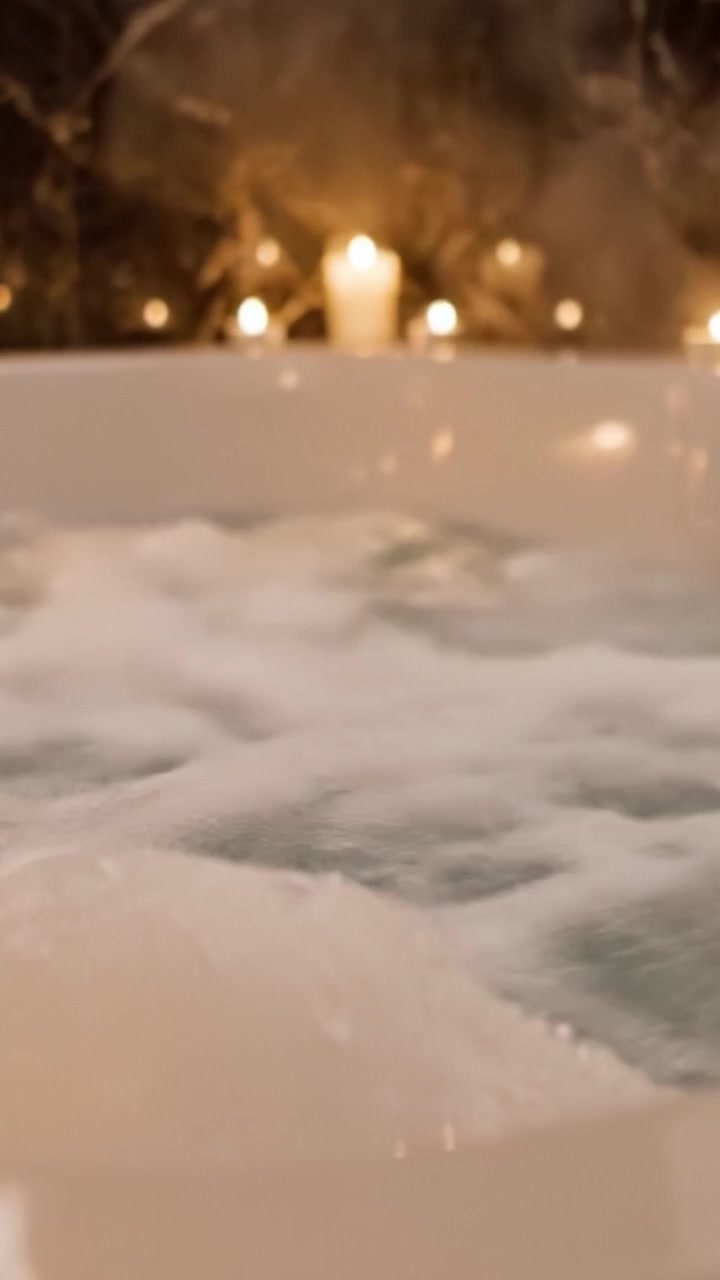 Relaxing Soak: A Serene Bubble Bath Experience with Candles Glowing in the Background, Perfect for Stress Relief and Pampering at Home.