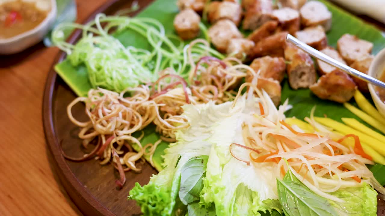 Primer plano cenital de salchicha de cerdo a la parrilla vietnamita tradicional servida con fideos y hierbas