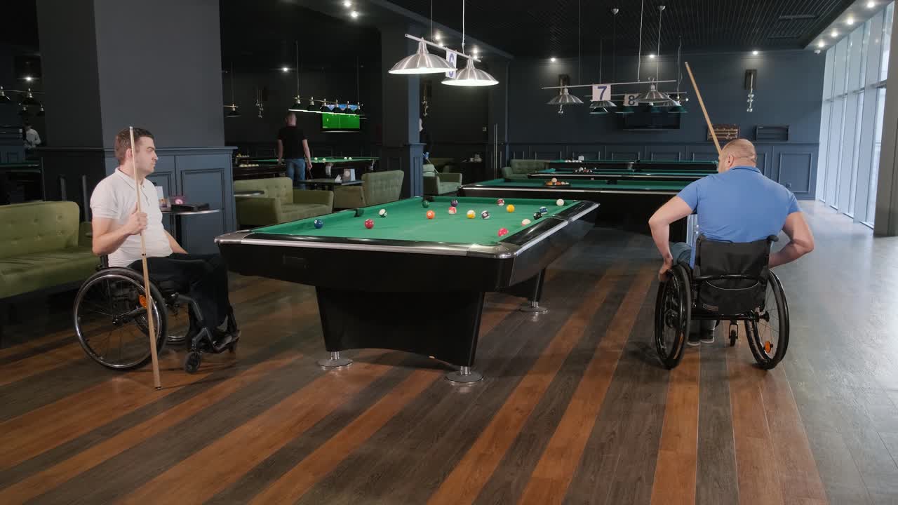 Uomini adulti con disabilità in sedia a rotelle giocano a biliardo nel club