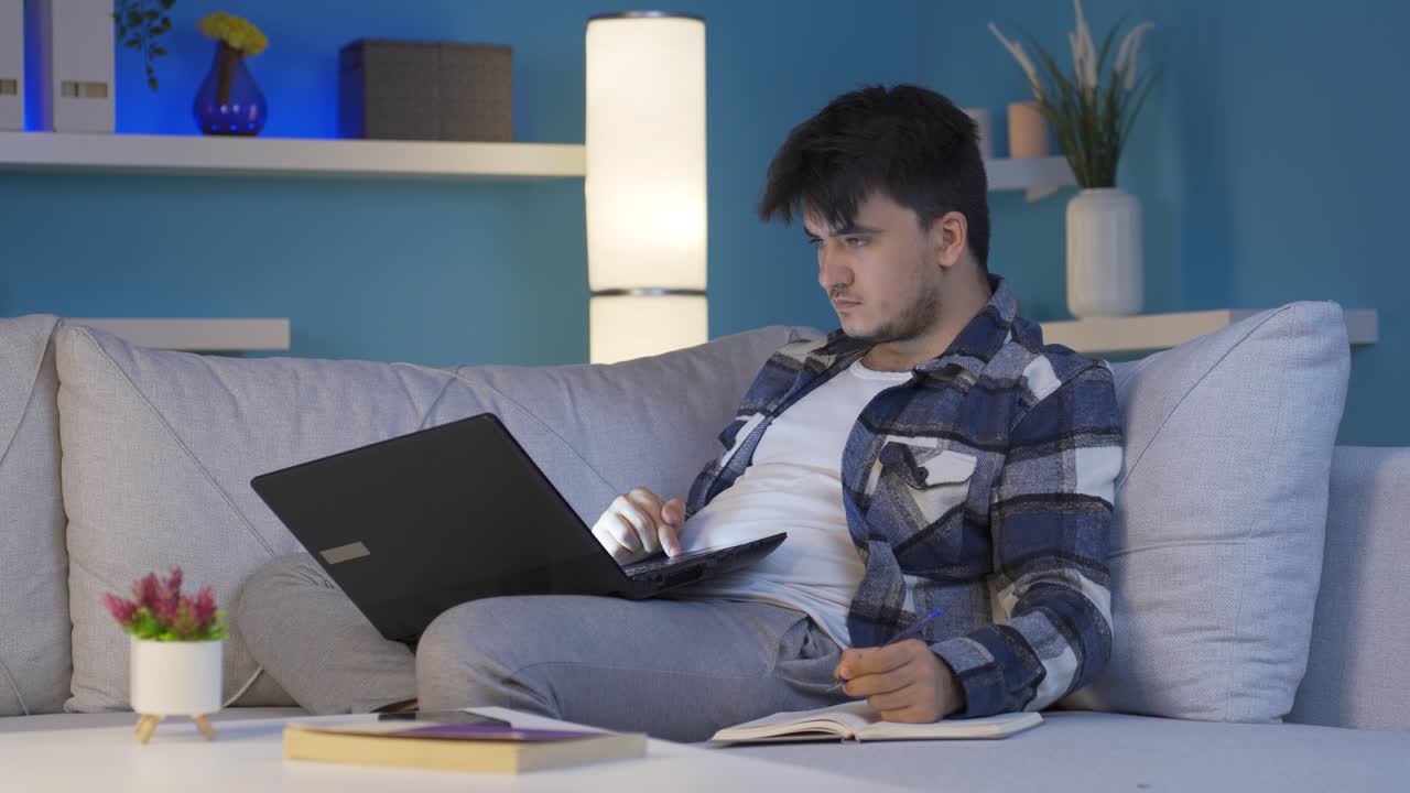 노트북 조명 속에서 밤에 공부하는 남성 학생.