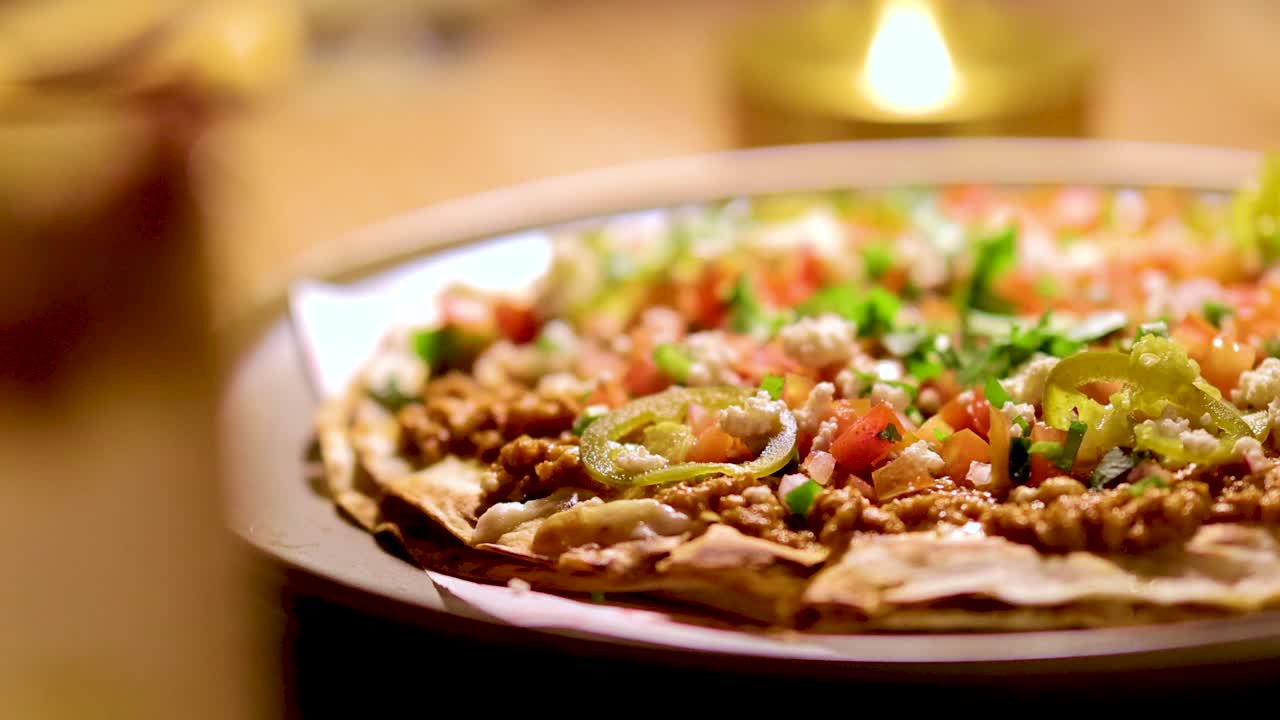 Mexican pizza on plate, candlelit restaurant table, shallow depth of field, slow camera pan