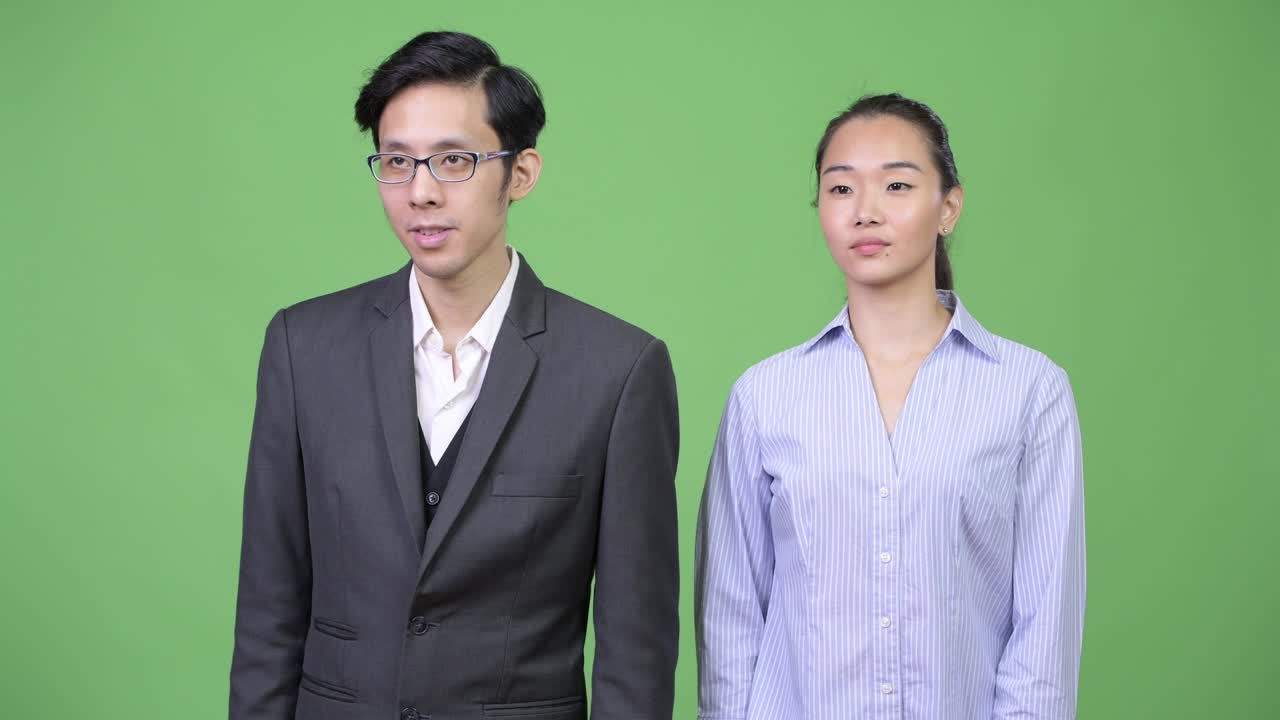 Young Asian business couple giving thumbs up together