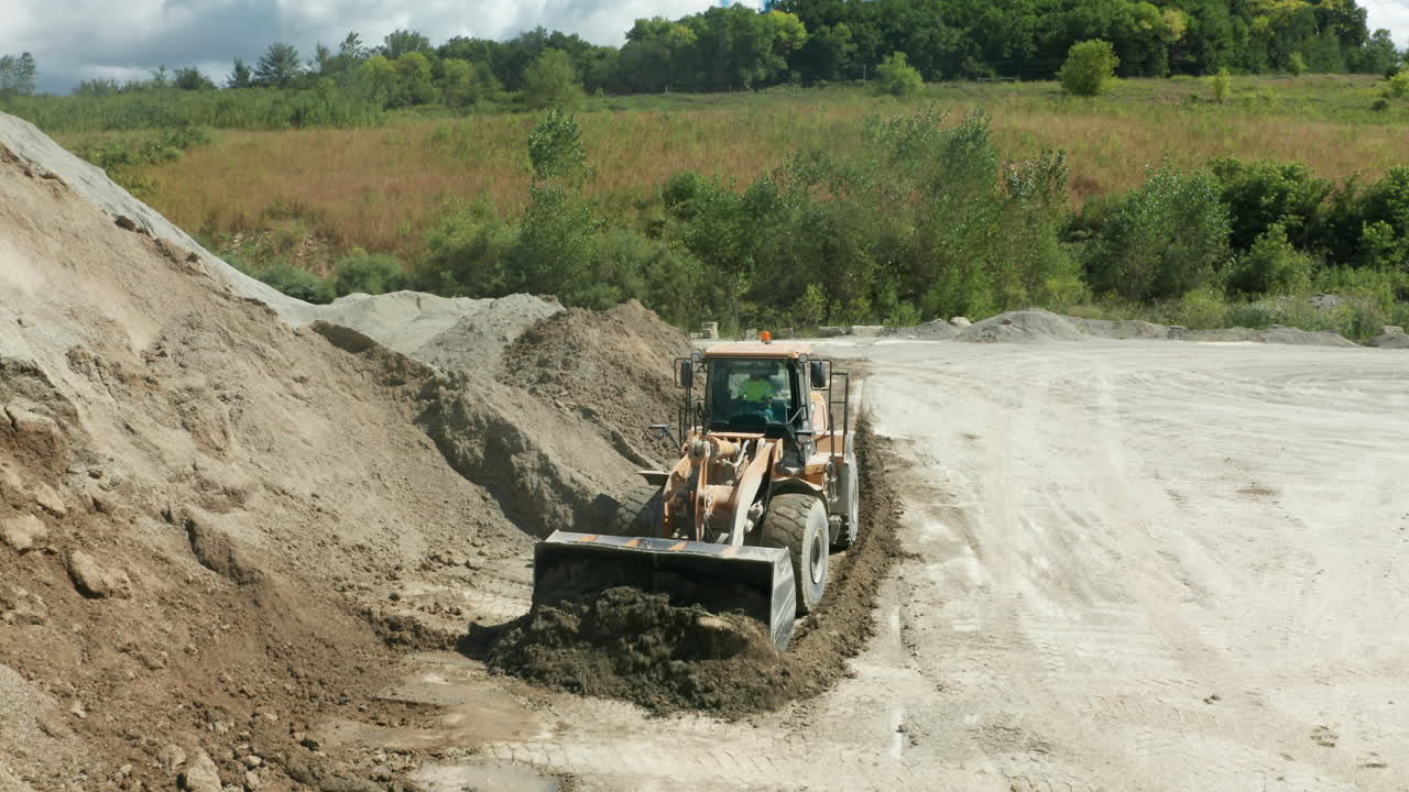 дневное воздушное изображение переднего погрузчика, консолидирующего сваи в карьере