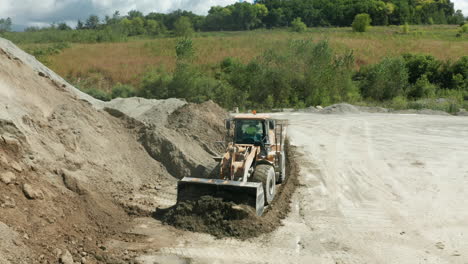 daylight aerial view of front end loader consolidating piles in quarry