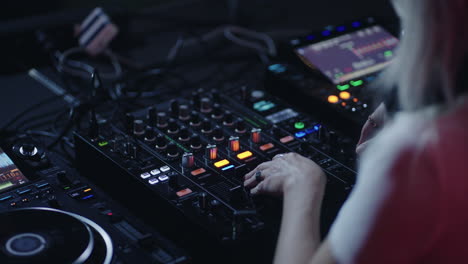 a woman dj mixes music on a console at a club.