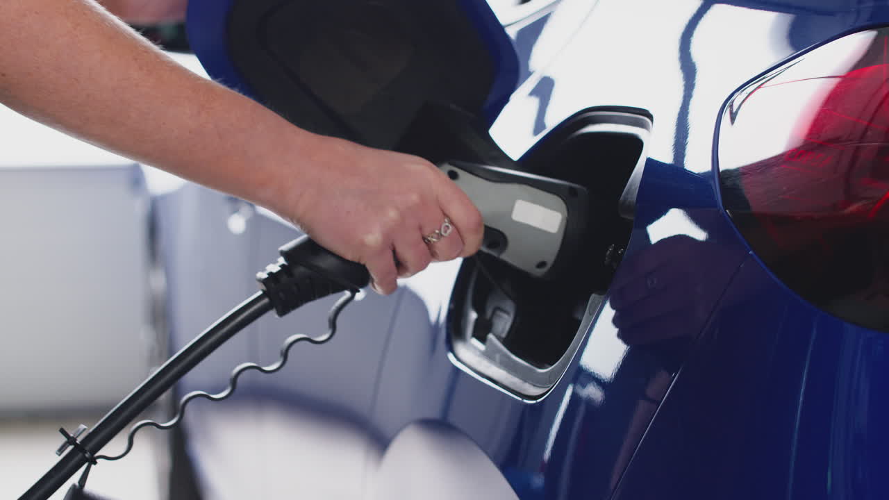 환경 친화적 인 제로 배출 전기 자동차에 충전 케이블을 연결하는 여성의 근접