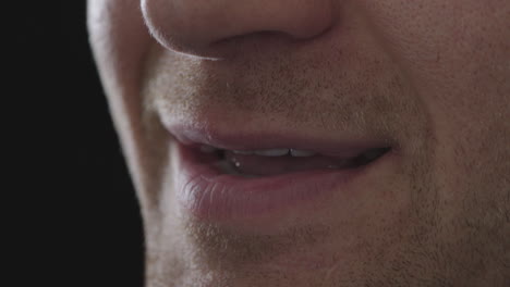 close up of man mouth smiling satisfaction isolated on black background