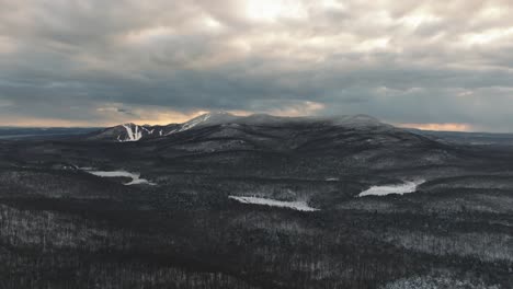 cloudy sky during sunset in snow-covered forest mountains in orford, canada