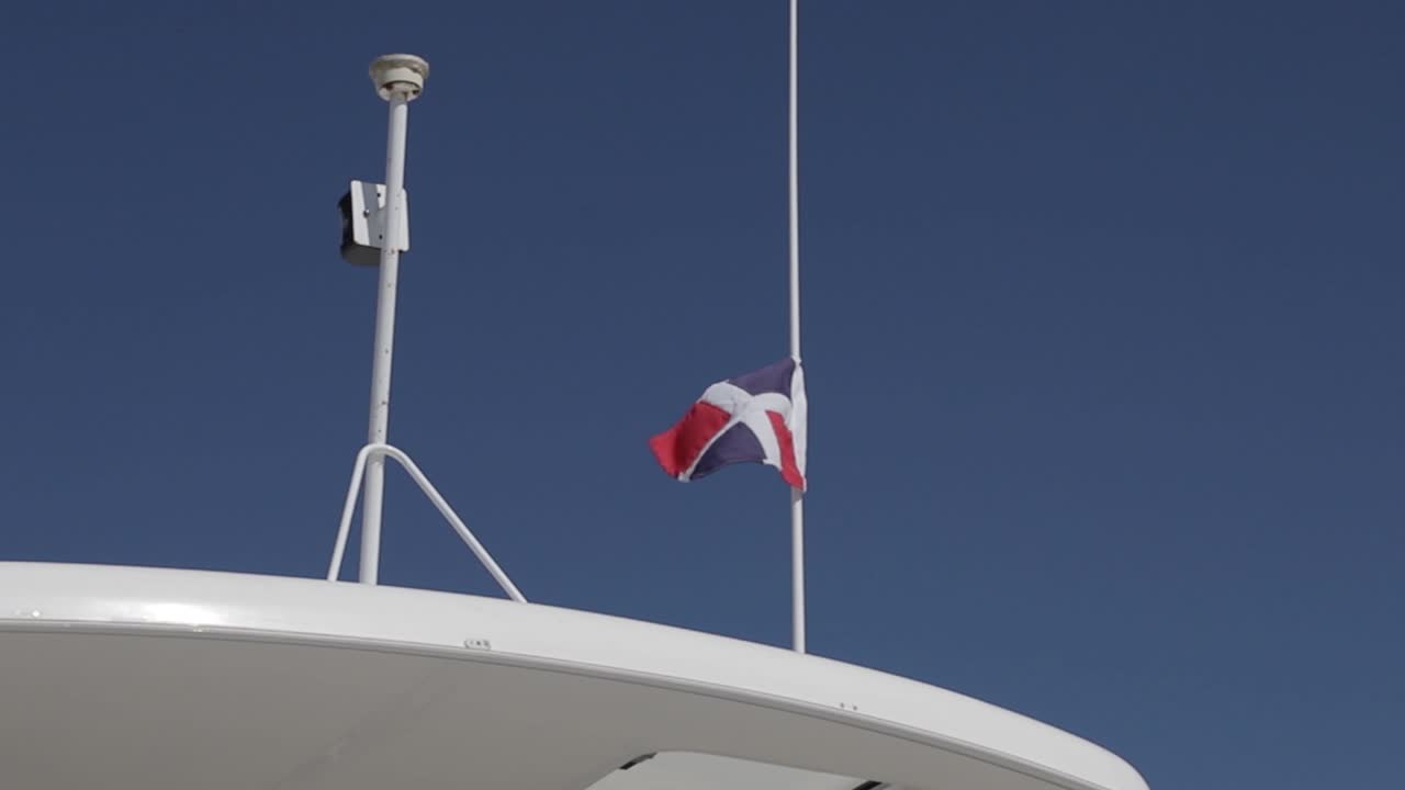 bandera de la república dominicana moviéndose en la brisa en un día soleado y encima de un yate