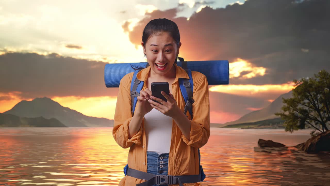 mujer turista emocionada con mochila mirando el teléfono al amanecer
