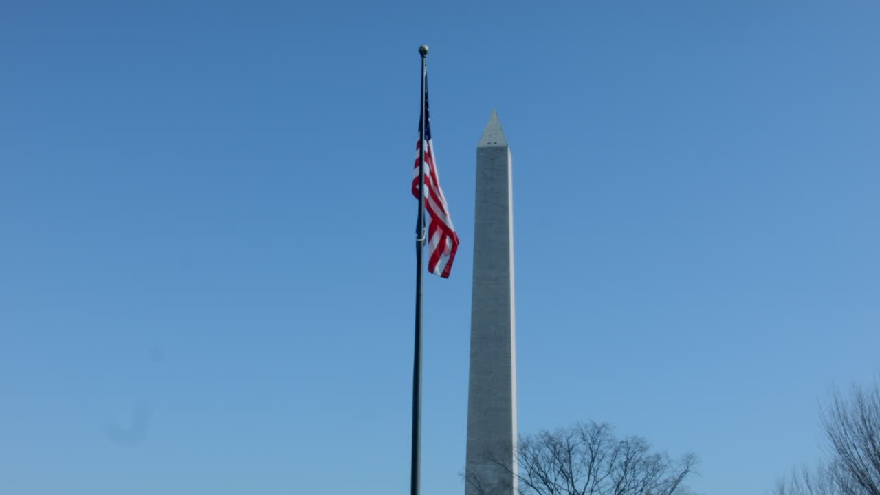 bandera americana ondeando al viento con el monumento a washington en el fondo