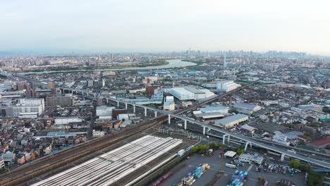 Vista-Aérea-Urbana-De-Japón,-Estación-De-Tren-Y-Autopista-Con-La-Ciudad-Al-Fondo