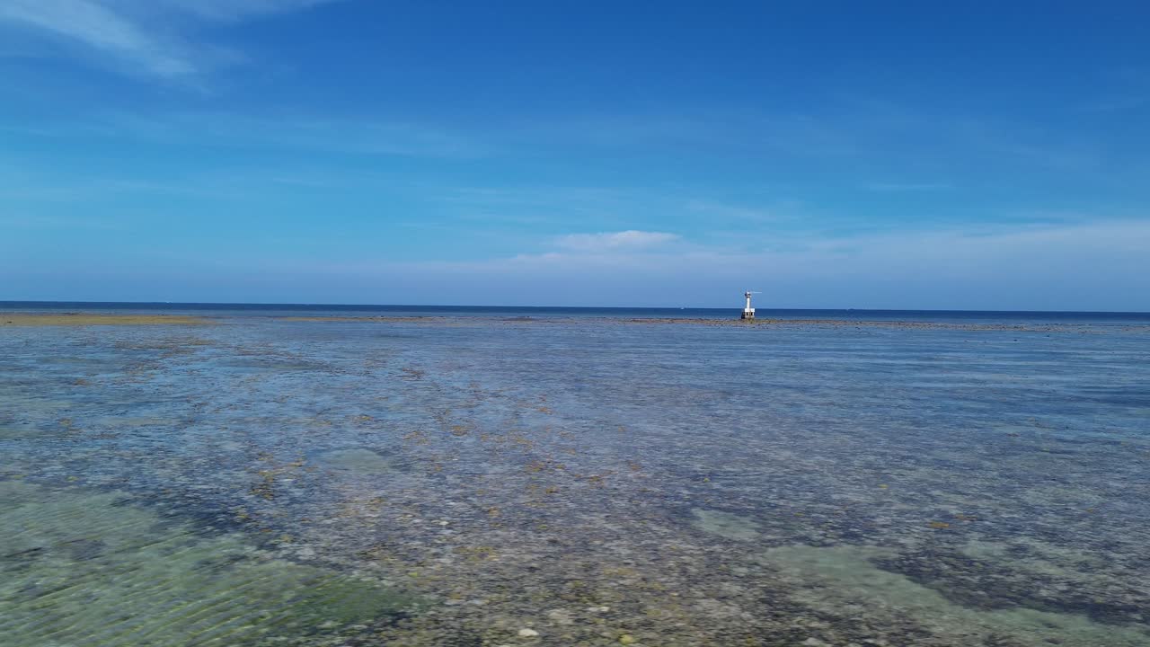 Drone performs a smooth orbit showcasing the vibrant coastline and surrounding landscape of My Hoa Lagoon in bright daylight.