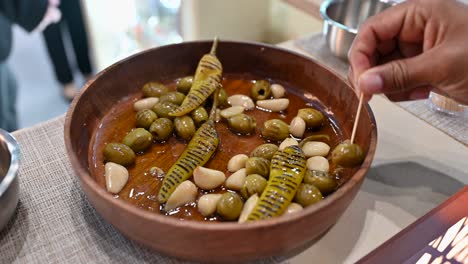 primer plano de aceitunas verdes a la parrilla, ajo y encurtidos de chile verde se muestran durante la comida del golfo 2023