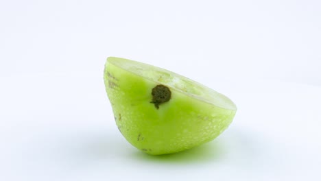 one half of green pepino with water drops. rotating on the turntable. isolated on the white background. close up. macro.