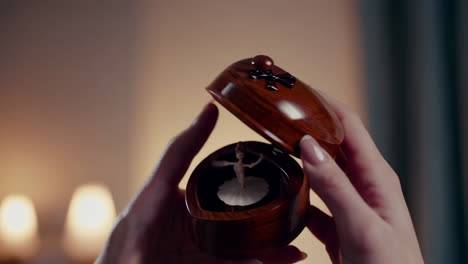 close-up of hands holding an open wooden music box with a spinning ballerina