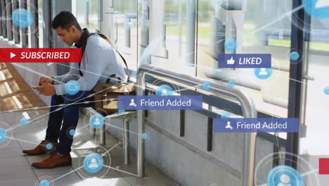 animation of digital and social media icons against biracial man using smartphone at bus stand