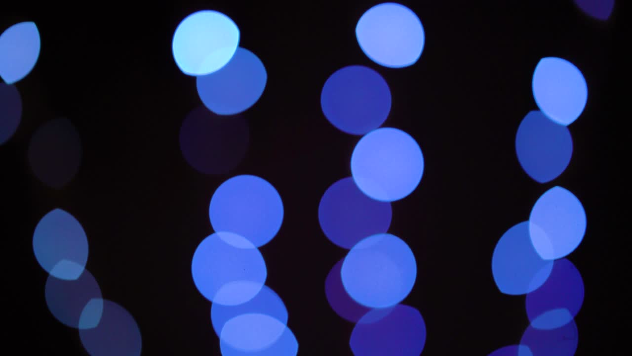 Bokeh blå lys, der stiger op i rækker på sort baggrund.
