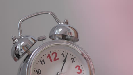 old fashioned alarm clock rings in the morning on a table . girl’s hand overturns the alarm so that it shuts up . sleeping girl waking up from alarm calling and turning it off . classic clock ringing