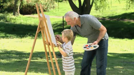 Little-boy-painting-a-white-canvas-with-grandfather