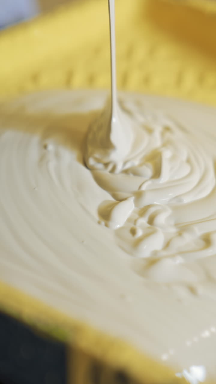 Light paint for home renovation. Worker pouring creamy color into a paint tray. Apartment decorating and home construction. Close-up. Vertical video