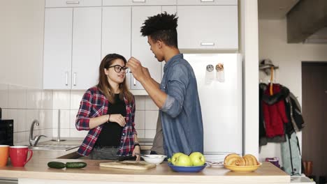 una pareja de dos jóvenes juguetones, con trajes urbanos modernos hipster, disfrutando de su tiempo juntos, bailando en la cocina.