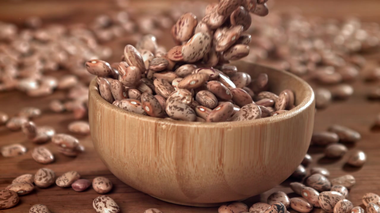 Slow Motion of Pinto Beans Filling a Wooden Bowl
