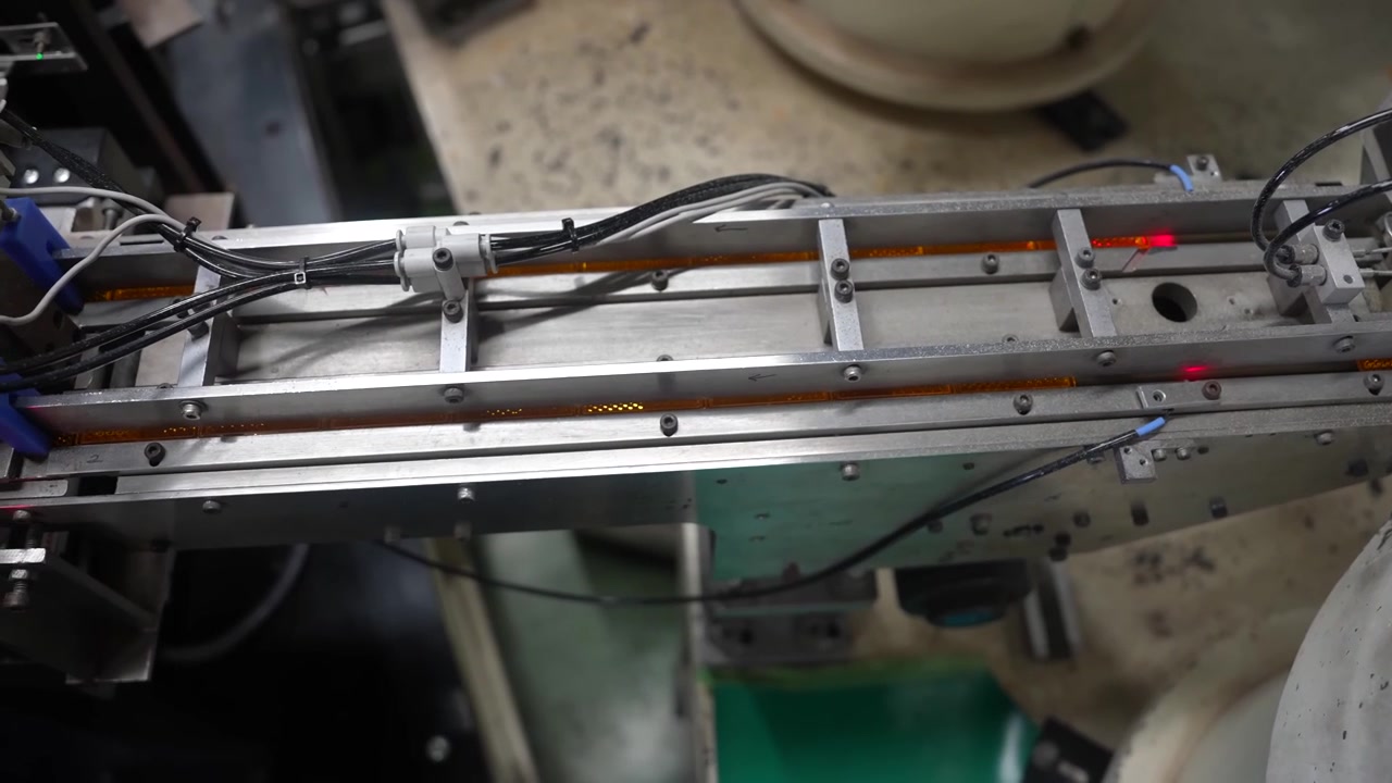 Primo piano di un nastro trasportatore lineare che trasporta parti in plastica stampate su una linea automatizzata.