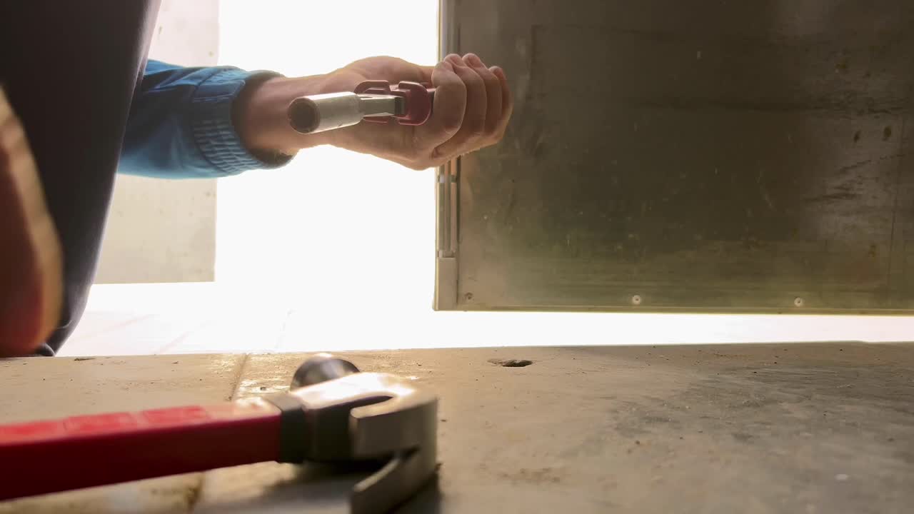 persona sta usando un martello sul sito di costruzione, con pinze lineman che tengono una vite metallica stretta per tirarlo fuori