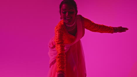 Studio-Shot-Of-Female-Kathak-Dancer-Performing-Dance-Wearing-Traditional-Indian-Dress-Against-Purple-Background-2