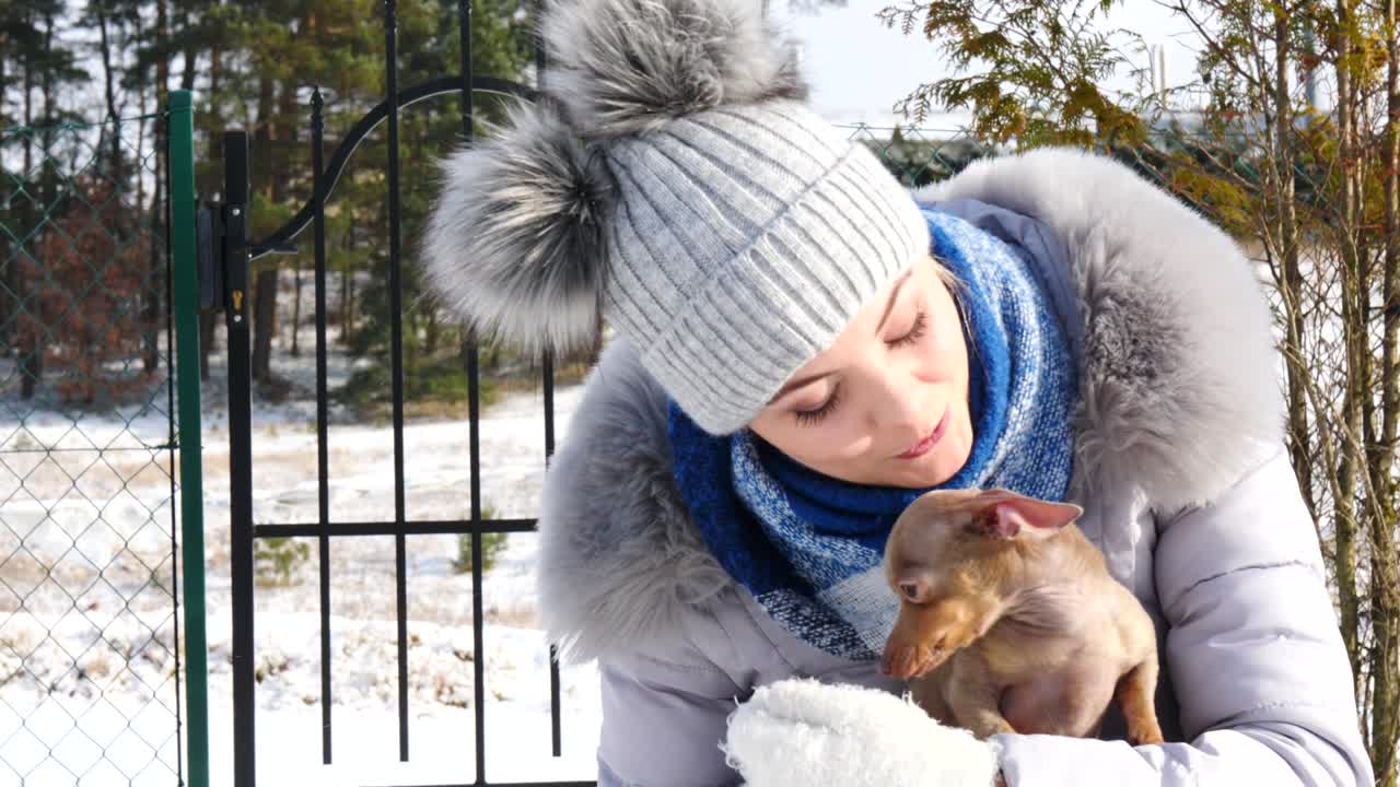 여자 는 겨울 밖 에서 작은 개 와 함께 놀고 있다