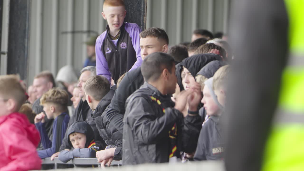 Fans are clapping and singing, voices loud, filling the air, vibrant crowd