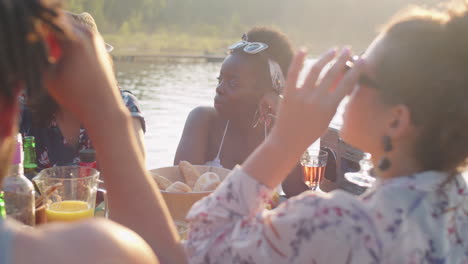 friends chatting at dinner table on lake party