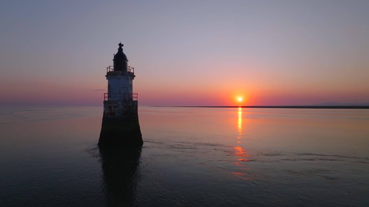 Derelict Lighthouse in very calm waters at sunset. Slow approach. Plover Scar Lighthouse, Lancashire, UK.