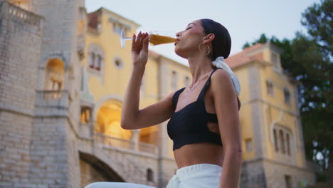 woman enjoying a drink in front of a beautiful castle