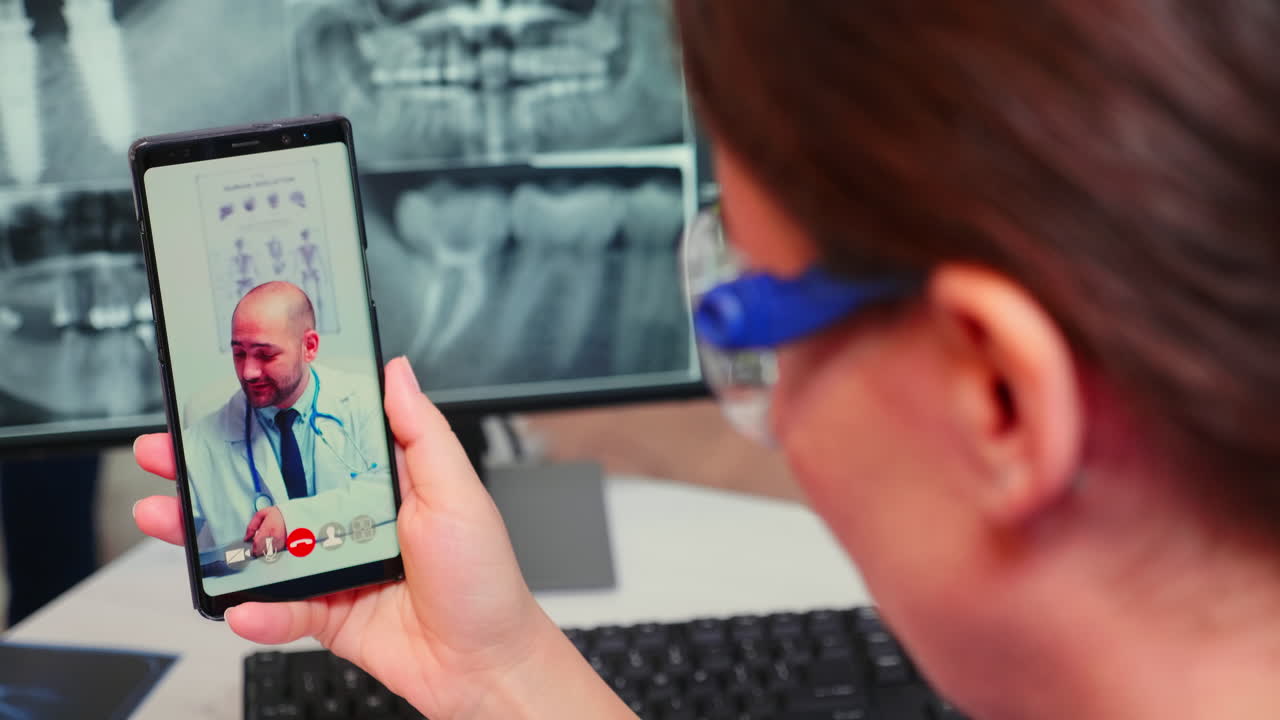 Primer plano de enfermera hablando en videollamada con un dentista especialista