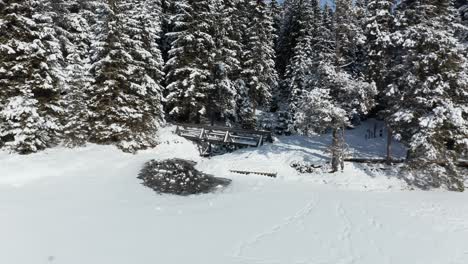 Wooden-footbridge-at-frozen-and-snow-covered-lake-in-winter,-Black-lake-or-Crno-jezero-on-Pohorje,-Slovenia