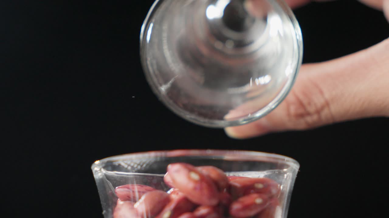 una ciotola di vetro di fagioli rossi viene versata in un'altra ciotola